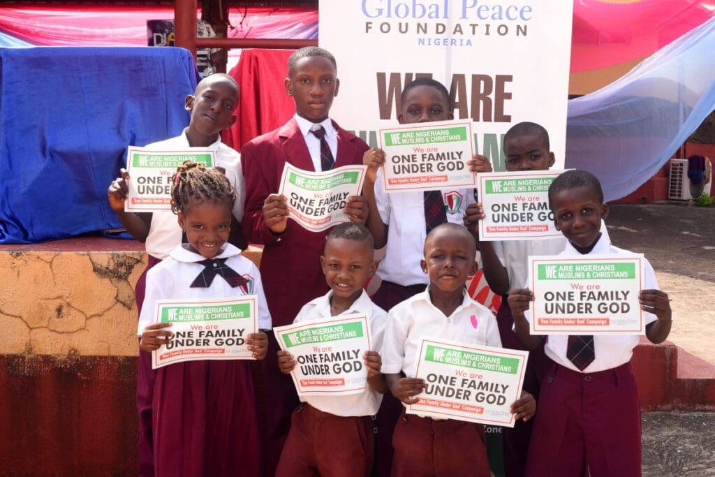 Seven school children in uniforms stand together, holding signs that read 