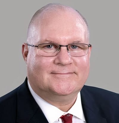 Col (Ret.) David Maxwell David Maxwell, a middle-aged man with glasses, a receding hairline, and a suit with a red tie, smiles at the camera against a plain gray background.