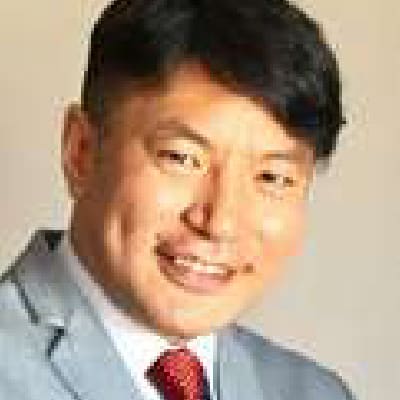 Dr. Nanjin Dorjsuren Dr. Nanjin Dorjsuren, dressed in a light gray suit, white shirt, and red tie, smiles at the camera against a neutral background.