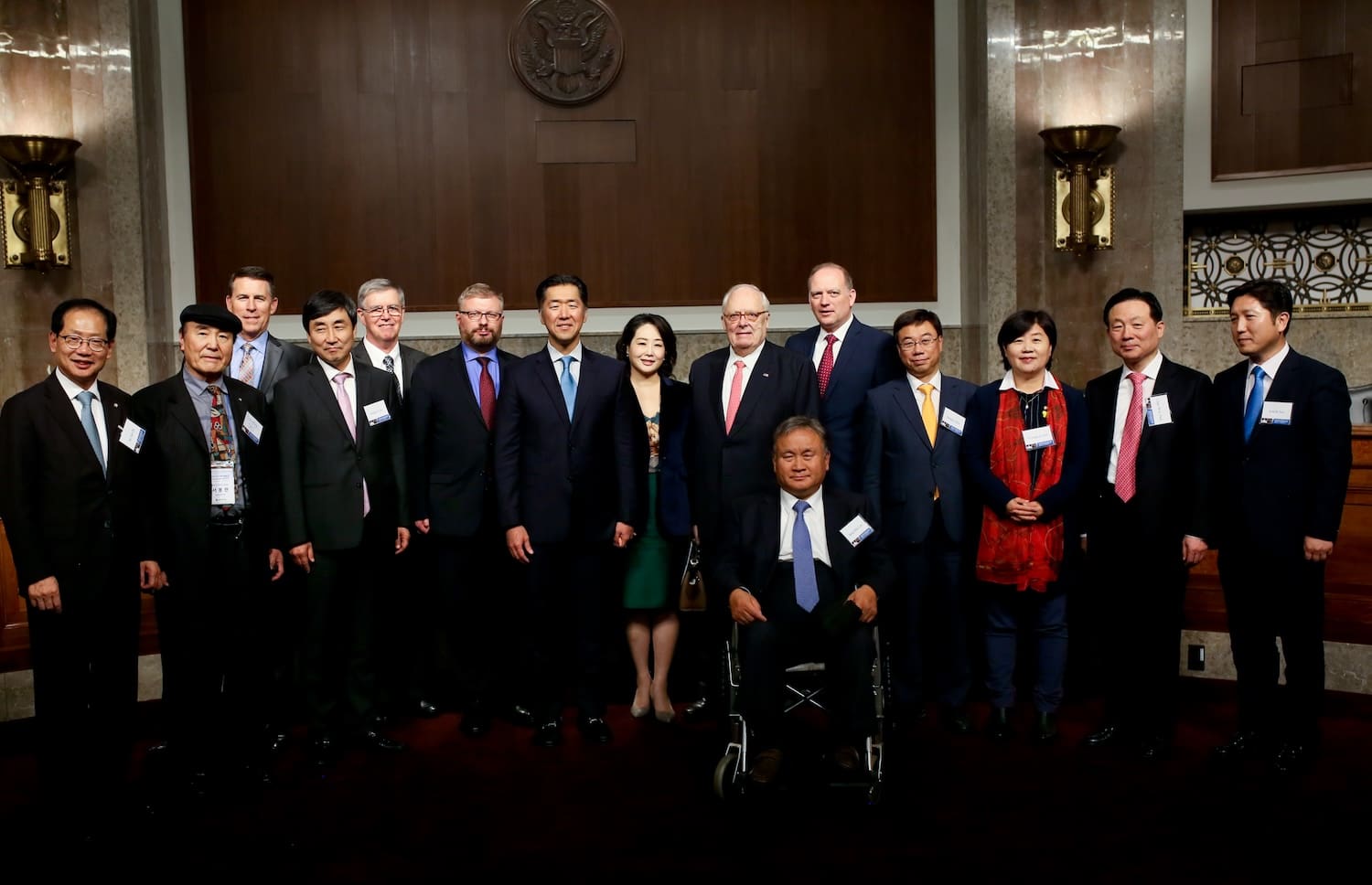 A group of thirteen people in formal attire pose together indoors, with one person seated in a wheelchair at the front—honoring Dr. Edwin J. Feulner on this special occasion.
