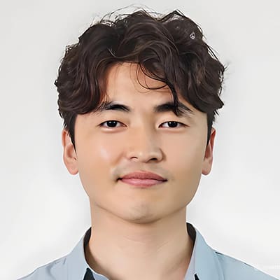 Kyungil Cho A man with wavy dark hair, light skin, and a slight smile is facing the camera against a plain white background—this is Kyung-Il Joh.