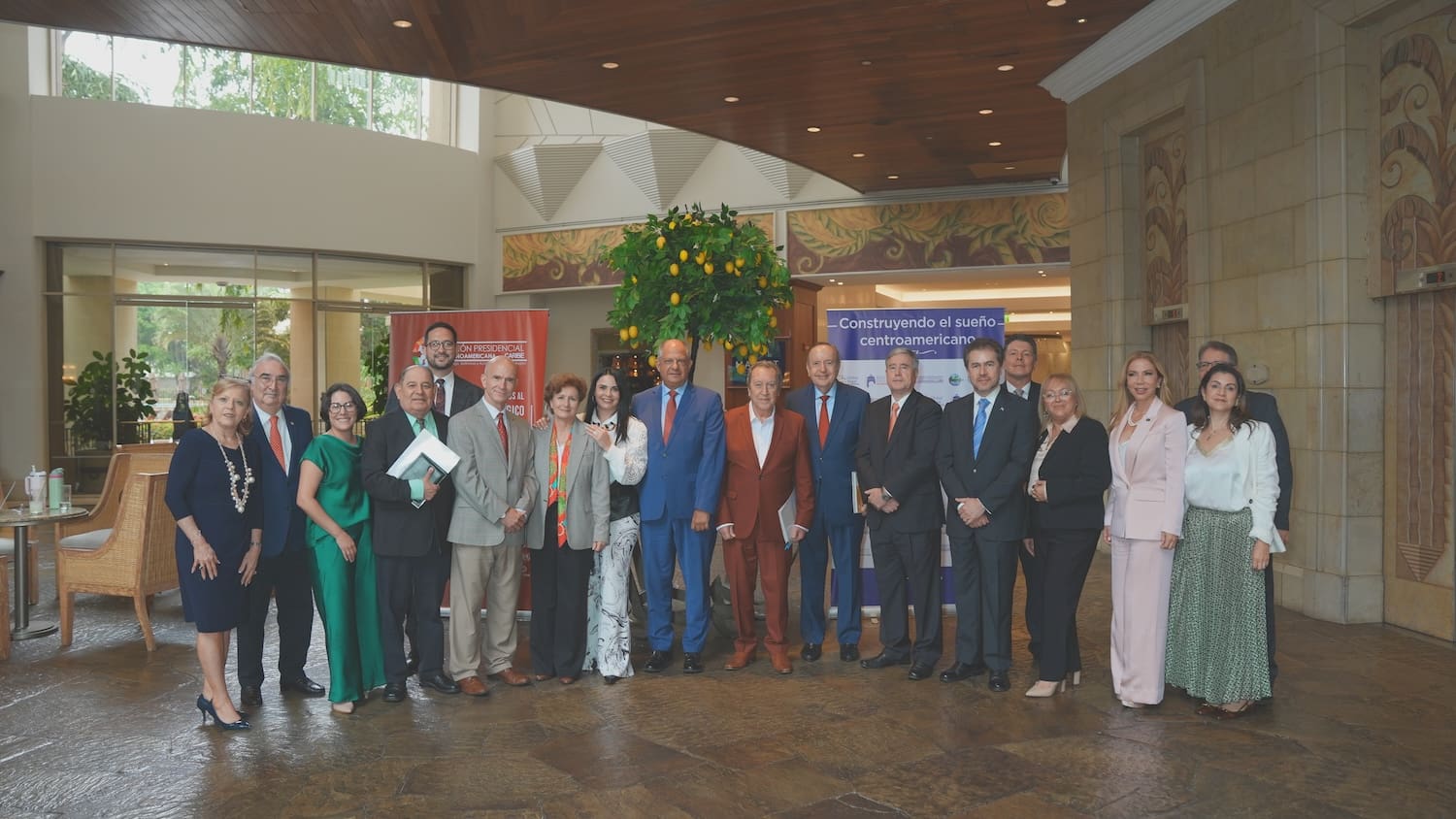 A group of people in business attire pose for a photo indoors in front of banners and greenery, highlighting a professional gathering focused on global geopolitics in Latin America.