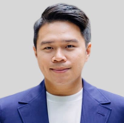 Leonard Faustino, a man with short dark hair, wears a navy blazer over a white shirt while facing forward against a plain light gray background.