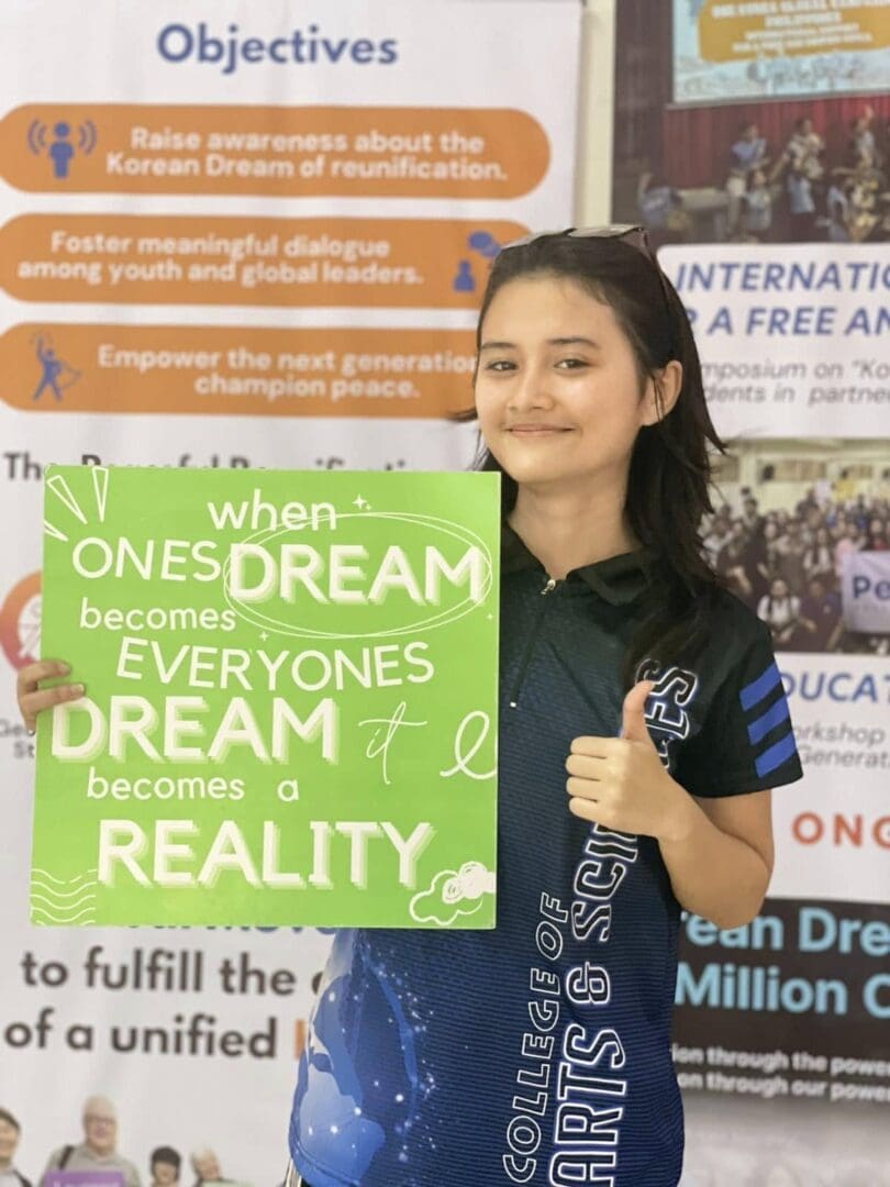 A young woman holding a green sign that reads