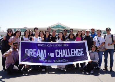 A group of people pose outdoors holding a banner that reads "Mongolia Youth Leadership Forum, Dream and Challenge, 2025 June 20-25, Mongolia," promoting dialogue on Northeast Asian Peaceful Development.