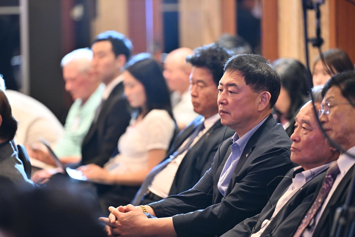 A group of people in business attire sit in rows, attentively listening at the Day 2 session of the One Korea 2025 International Forum.