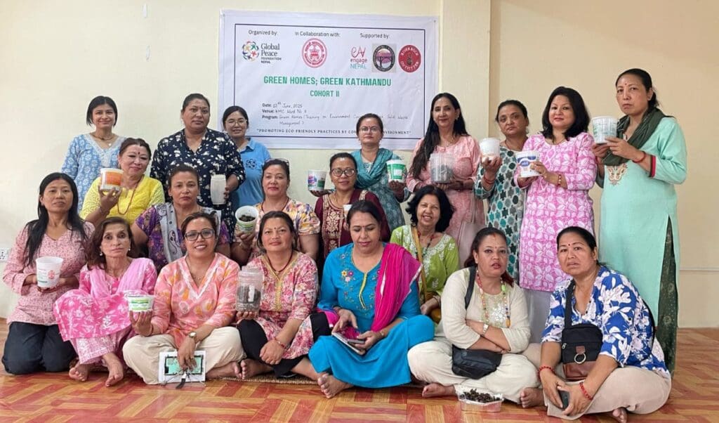 A group of women pose indoors, some holding potted plants and containers, in front of a Green Homes event banner for the Green Kathmandu Project by GPF Nepal.