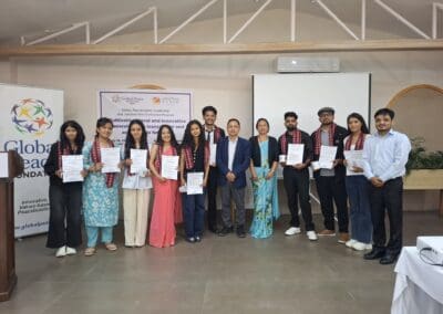 A group of people pose indoors, several holding certificates. A banner for the Global Peace Foundation and GPF Nepal is visible in the background, highlighting participants of the Global Peacebuilders Leadership Program.