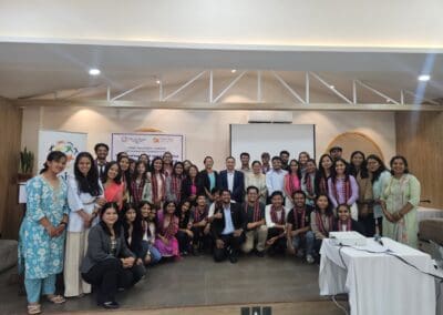 A large group of people, mostly young adults, pose together indoors in a conference room, some wearing ceremonial scarves, with banners for the GPF Nepal Global Peacebuilders Leadership Program and Saksham Nari Fellows visible in the background.