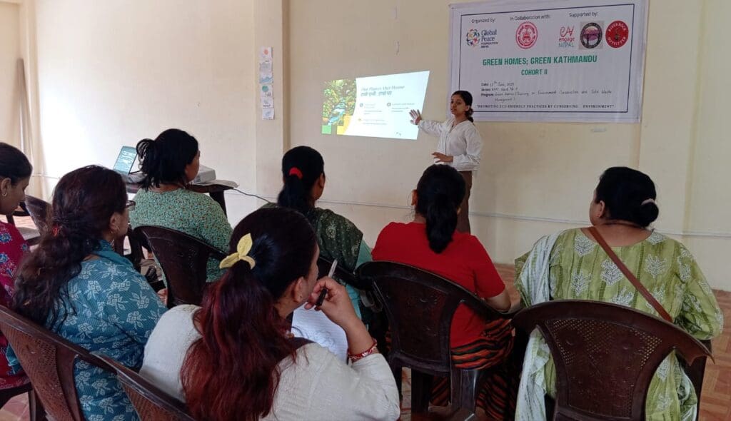 A woman gives a presentation on Eco-Friendly Training to a group of seated women in a classroom setting, with a screen and Green Kathmandu Project banner in the background.