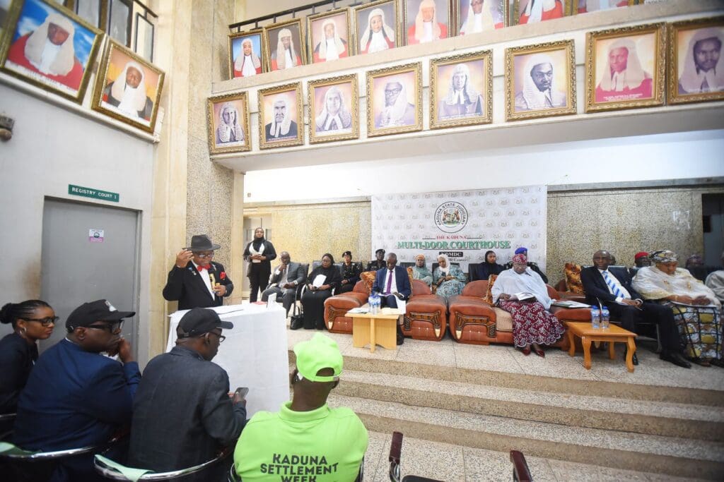 A formal gathering in a Kaduna courtroom with people seated and standing; portraits of judges line the walls above the participants, reflecting the importance of Peaceful Reconciliation and Alternative Dispute Resolution.