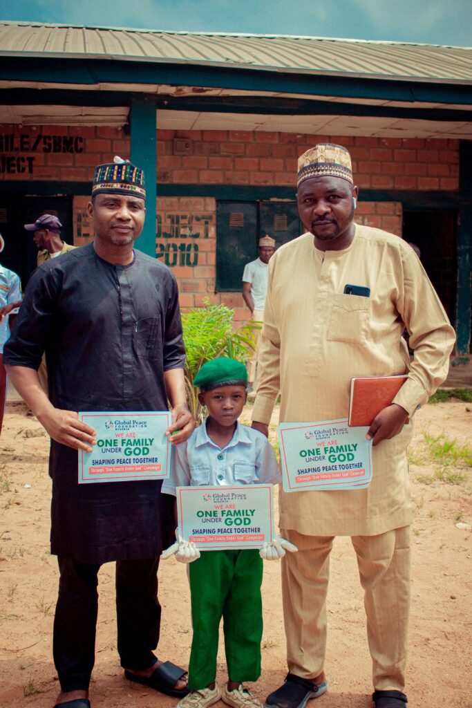 Three people pose in front of a brick building at the Community Peace Forum. Two adults hold signs that read 