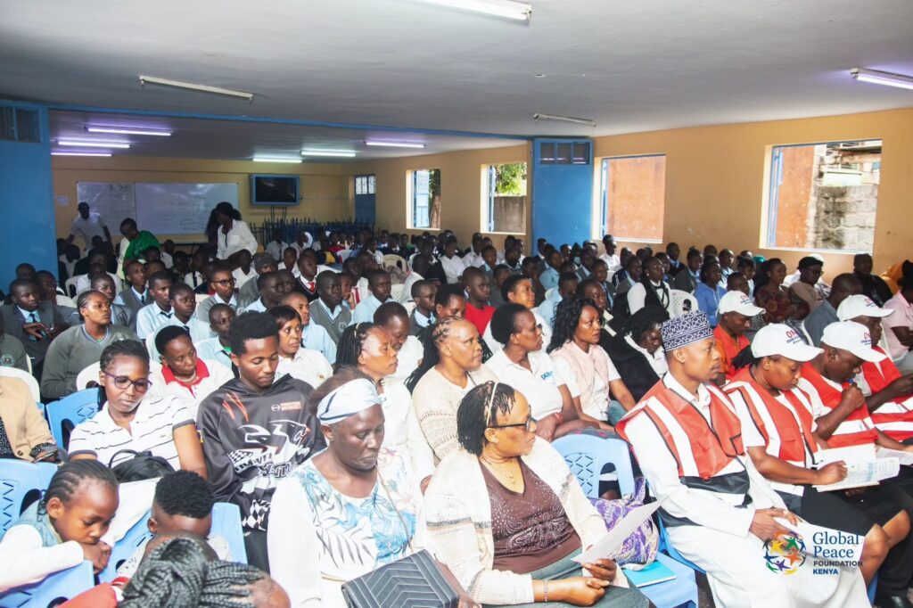 A large group of people sit closely together in a bright room, attending a Peace event hosted by the Global Peace Foundation Kenya (GPF-Kenya).