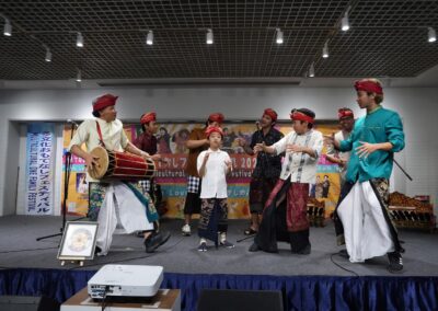 A group of men and a child in traditional attire perform with drums and gestures on stage at the One Family Festival 2025, celebrating multicultural festival traditions.