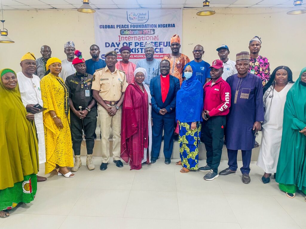 A diverse group of people stand together, posing for a photo at an event in Niger State with a banner reading