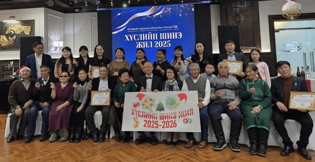 A group of people, part of GPF Mongolia, pose indoors holding certificates and a banner that reads