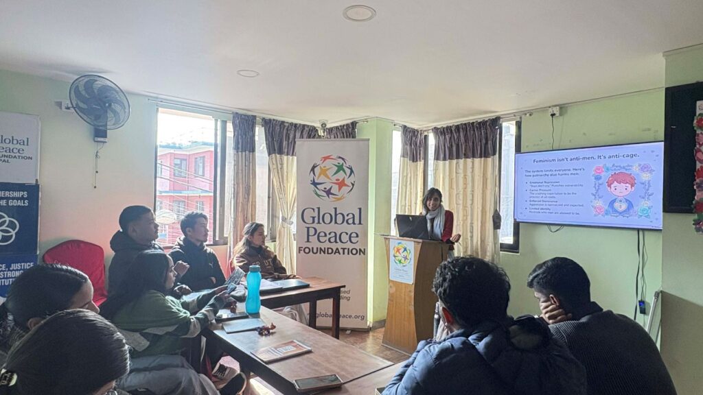 A woman gives a presentation to a small group of Young Leaders seated around tables in a room with