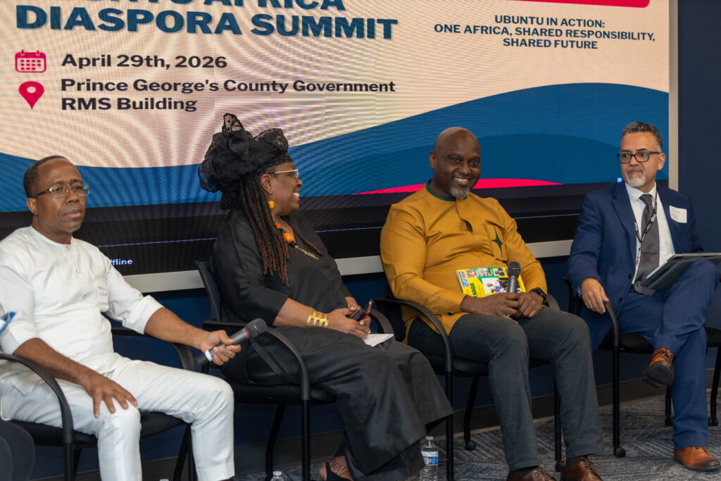 Four panelists sit on stage at the 2026 Diaspora Summit, hosted by Ubuntu Africa Gallery, with event details displayed on a screen behind them.