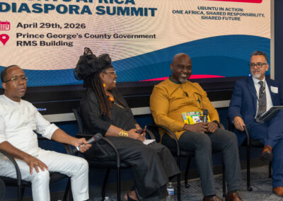 Four panelists sit on stage at the 2026 Diaspora Summit, hosted by Ubuntu Africa Gallery, with event details displayed on a screen behind them.