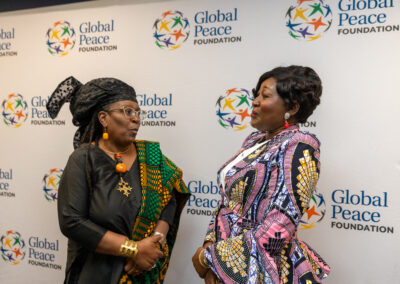 Two women in colorful traditional attire converse in front of a Global Peace Foundation backdrop at the Ubuntu Africa Diaspora Summit 2026.