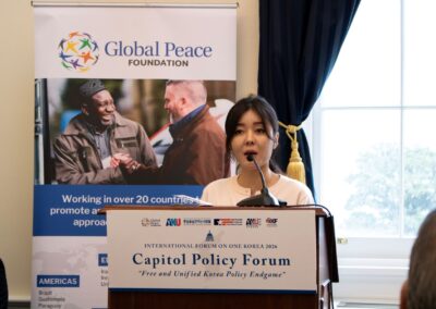 A woman speaks at a podium during the Capitol Policy Forum, part of the International Forum on One Korea, with a Global Peace Foundation banner displayed in the background.
