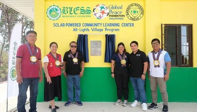 Six people stand in front of a yellow and green building labeled 