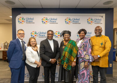Six people stand together smiling in front of a Global Peace Foundation banner at an indoor event during the Ubuntu Africa Diaspora Summit.