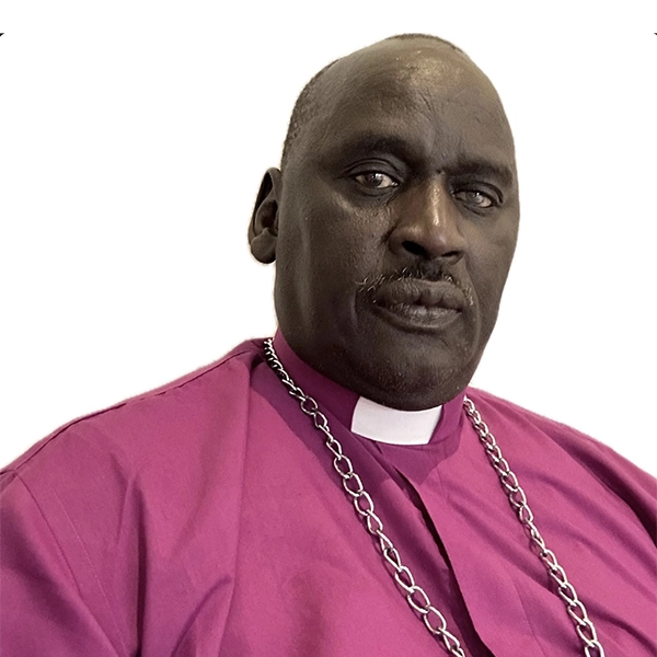 Bishop Isaiah Majok Dau, wearing a purple clerical robe and a silver chain collar, looks at the camera with a neutral expression against a plain white background.