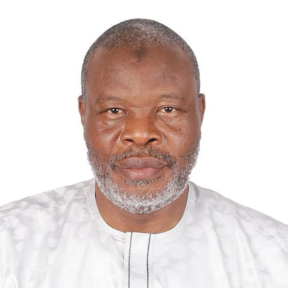 Ustaz Abubakr Siddeeq Muhammad, a middle-aged man with a short gray beard and hair, wearing a white patterned shirt, poses against a plain white background.